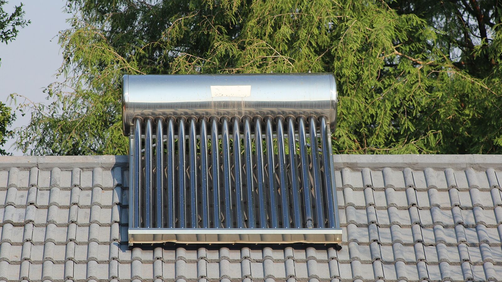Evacuated tube solar water heater with a stainless-steel storage tank on a tiled roof