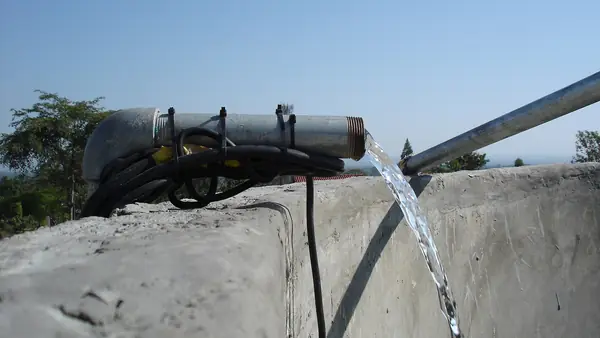 Water from a solar-powered pump flowing into a concrete storage tank in Otho Abwao, Kenya